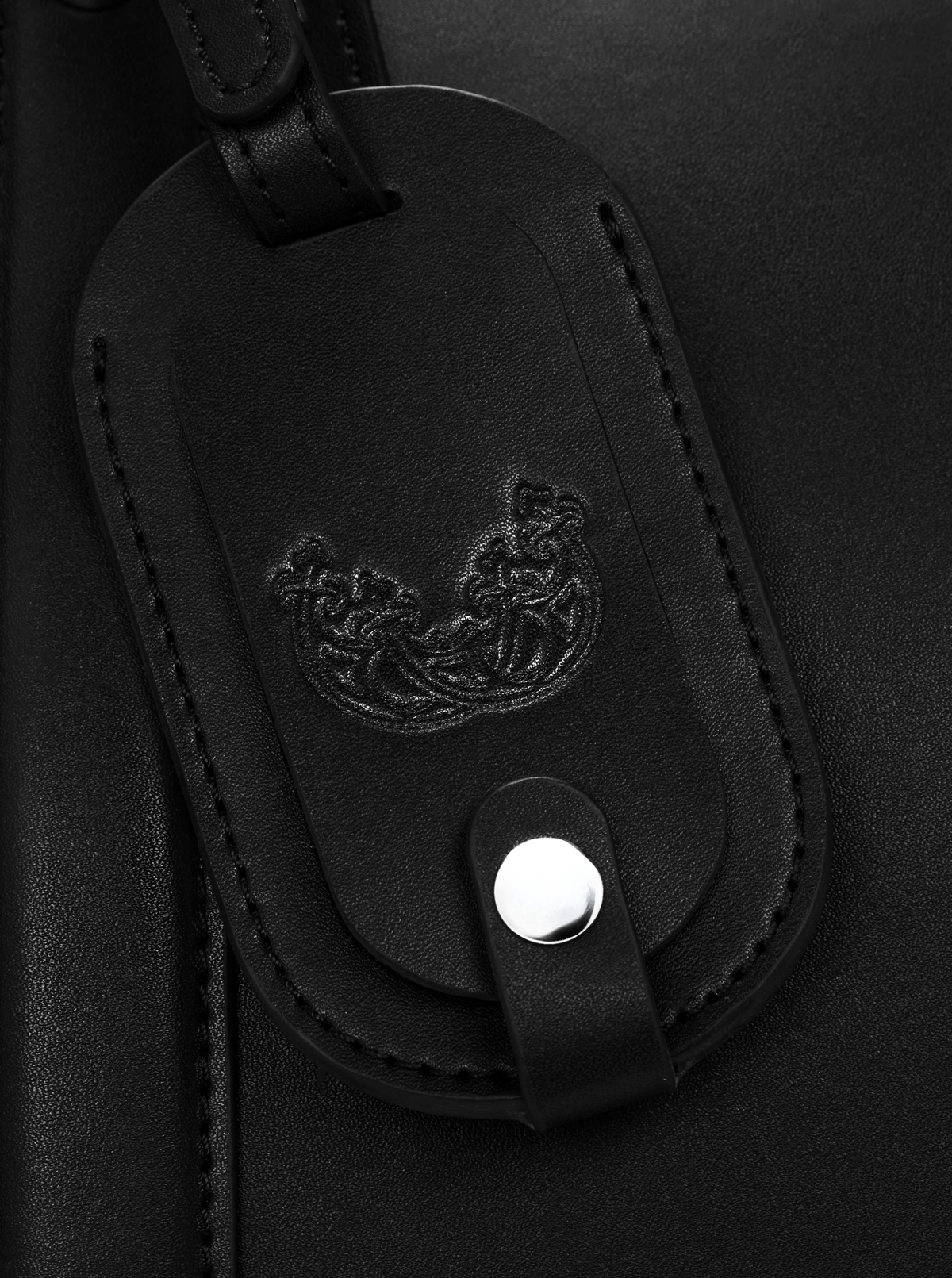 Detailaufnahme des geprägten Wellen-Signets auf dem Lederanhänger der MAGVELY 50 Weekender Tasche